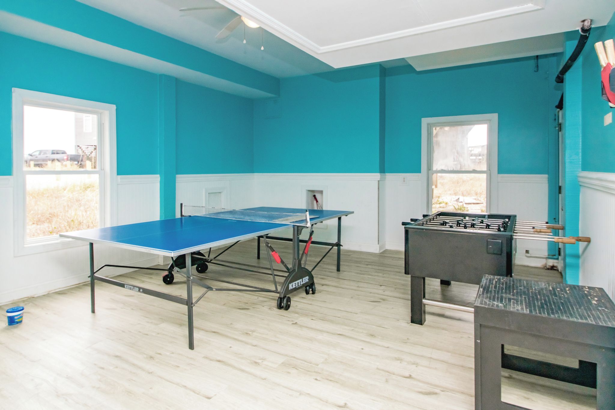 Una habitación con mesa de ping pong, mesa de fútbolín y ventana con vista al exterior.