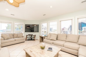 A living room with a beige sofa, a wooden coffee table, and a TV mounted on the wall. - @ THE PEACH offers an escape to an oceanfront/oceanside (North Topsail Beach)