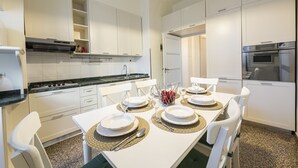 A modern kitchen with white cabinets, a black countertop, and a dining table set for four.