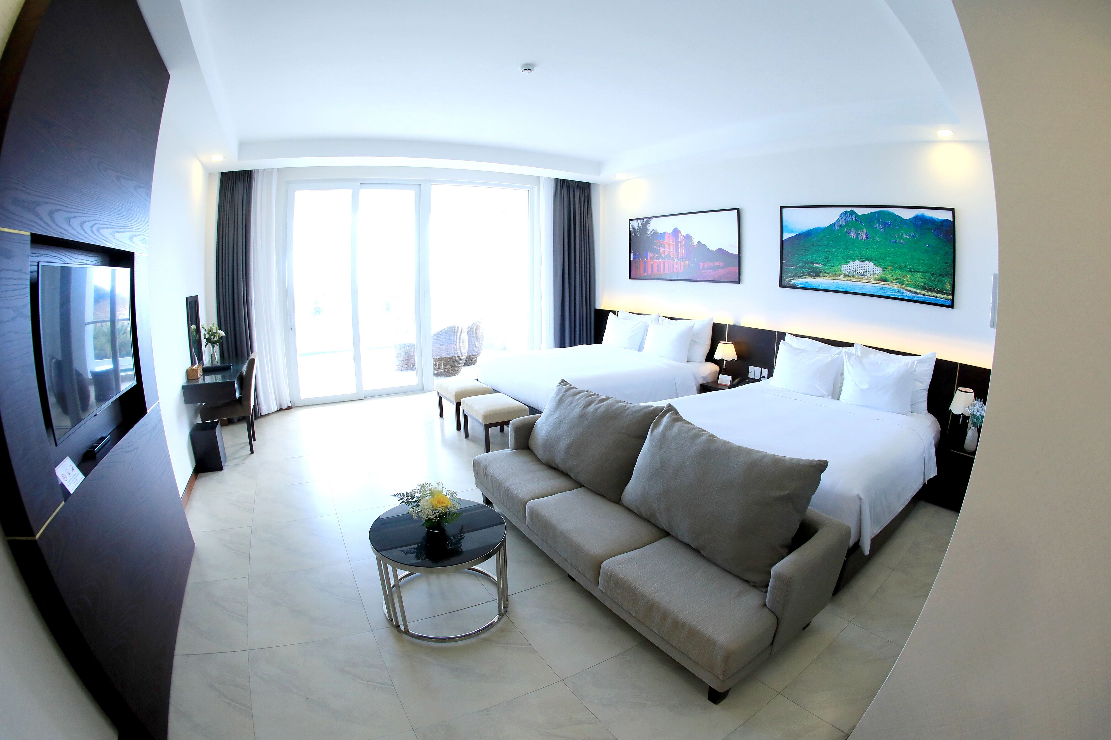 A hotel room with a bed, a sofa, a TV, and a large window.