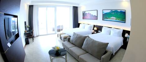 A hotel room with a bed, a sofa, a TV, and a large window.