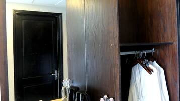 Ein Hotelzimmer mit einem hölzernen Schminktisch, einem Spiegel, einem aufgehängten Bademantel und Toilettenartikeln auf der Ablagefläche.