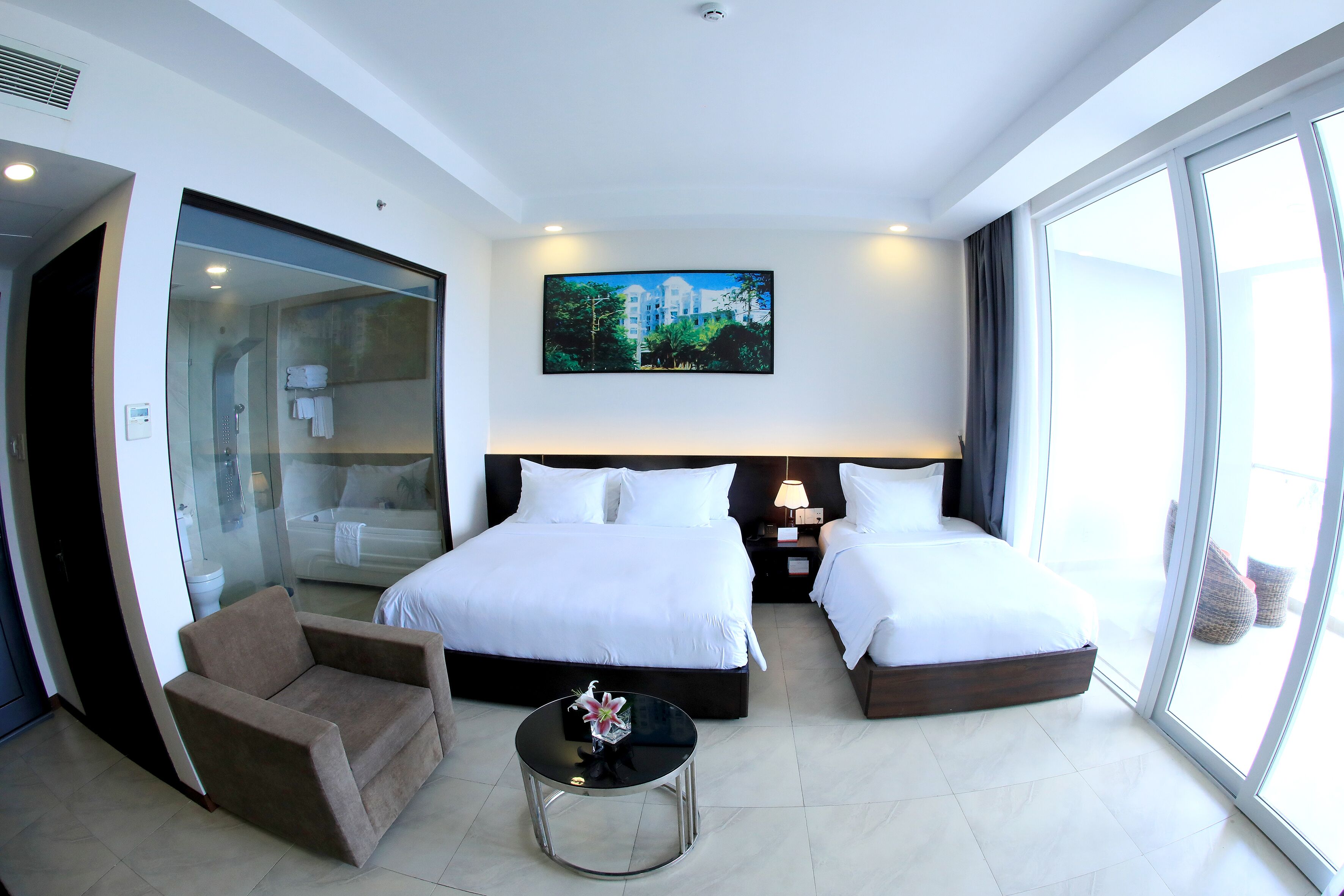 A hotel room with two beds, a sofa, a small table, and a large window.