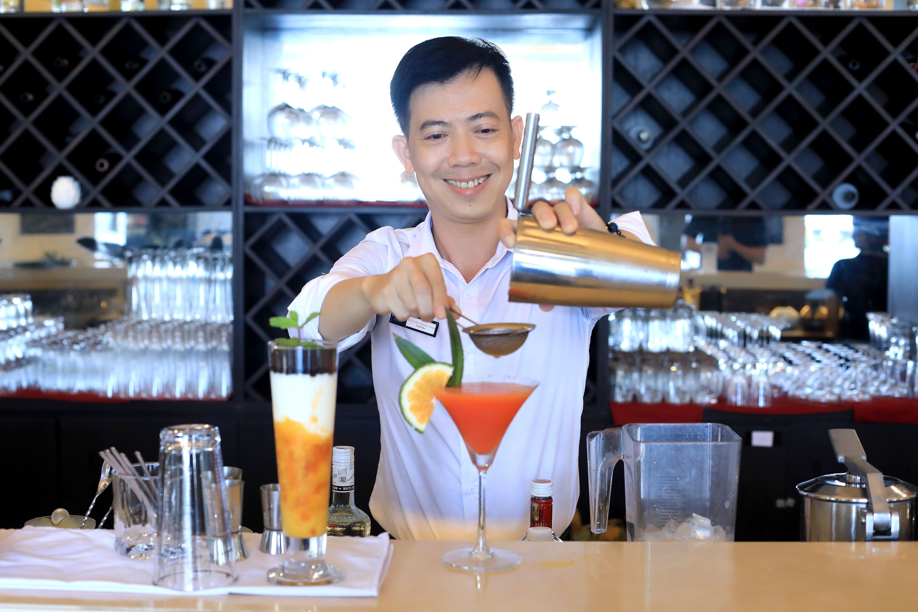 A bartender preparing a cocktail with a lime garnish.