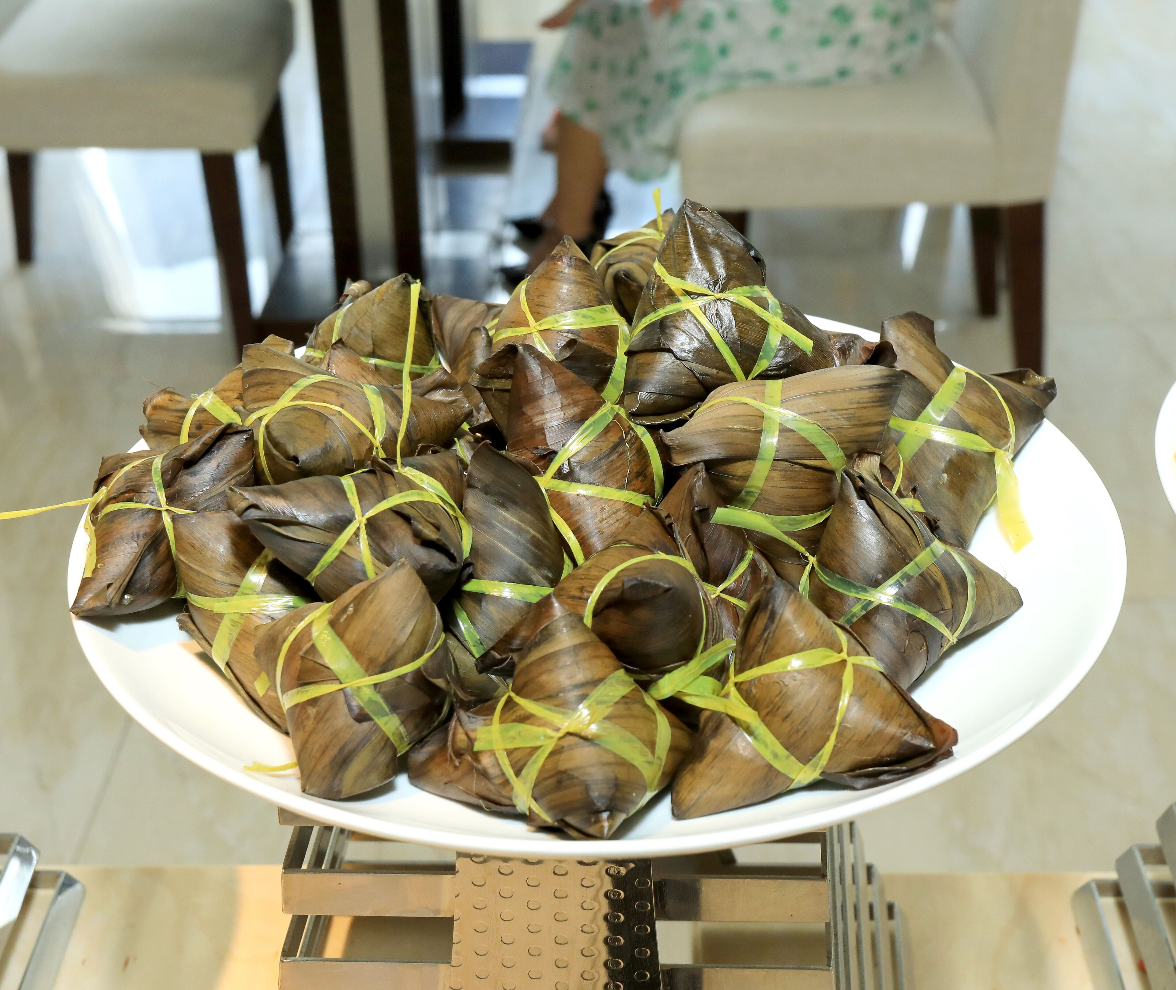 Une assiette de nourriture enveloppée dans des feuilles et attachée avec des liens verts, posée sur une table.