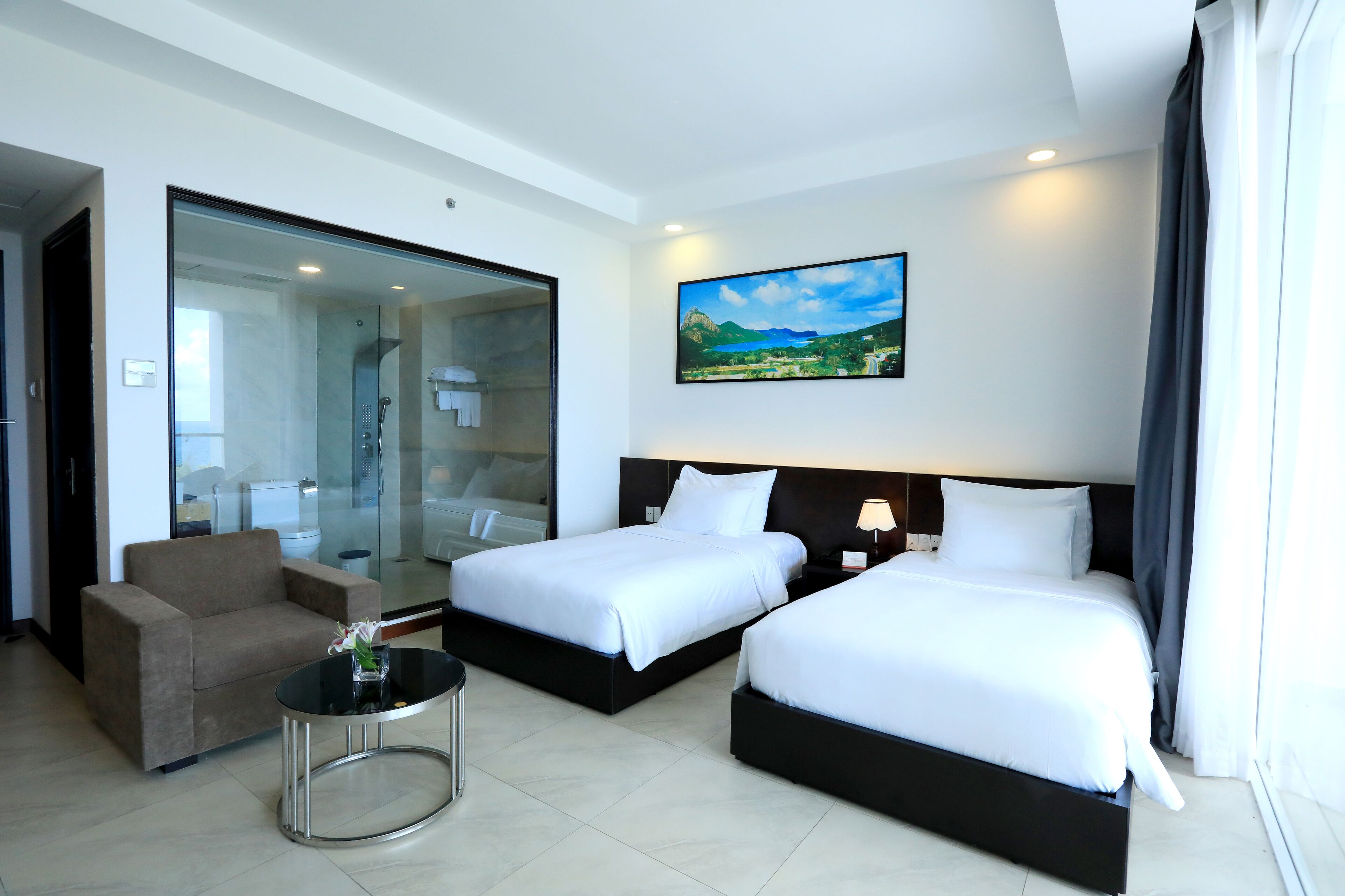 A hotel room with two beds, a sofa, a small table, and a painting on the wall.