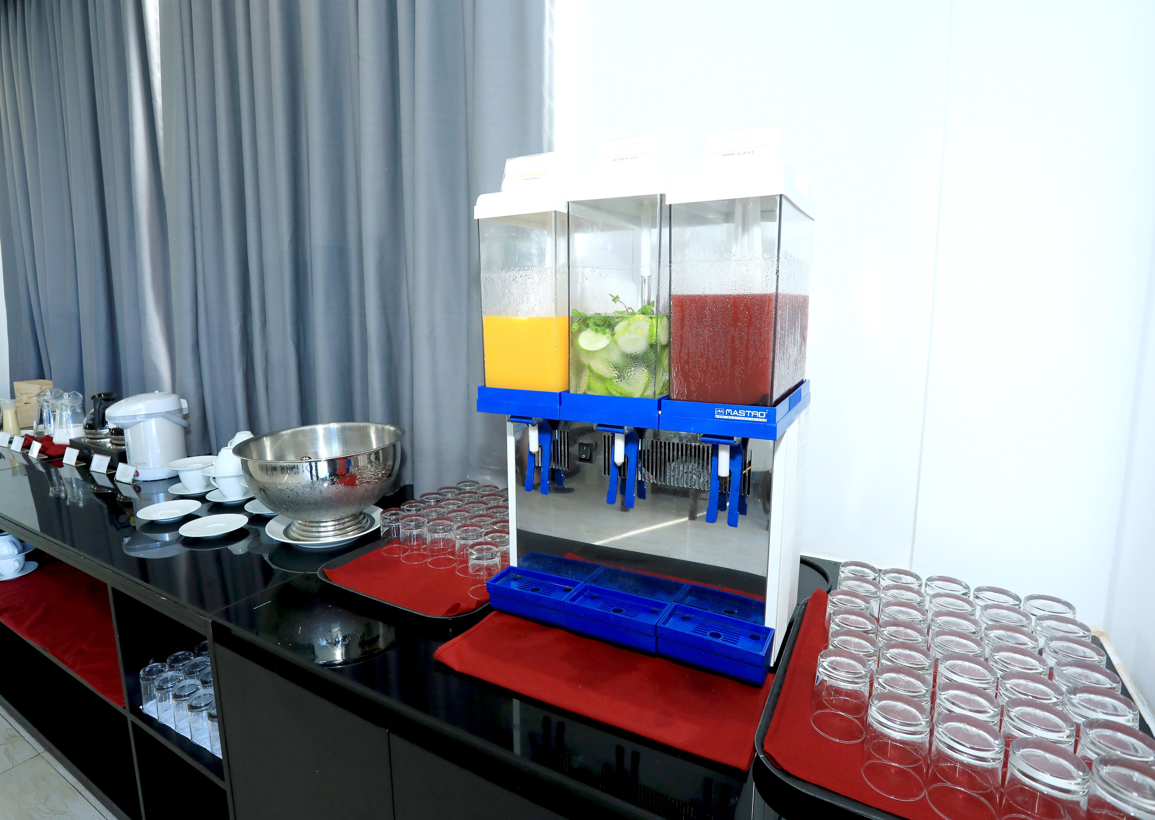 A bar area with a beverage dispenser, a large mixing bowl, and various glassware.