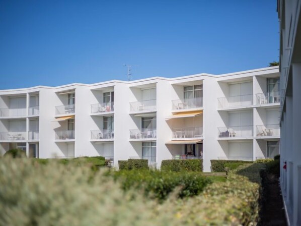 A multi-story hotel with balconies, a clear sky, and well-maintained landscaping. - Les Trois Iles by Interhome (Quiberon)