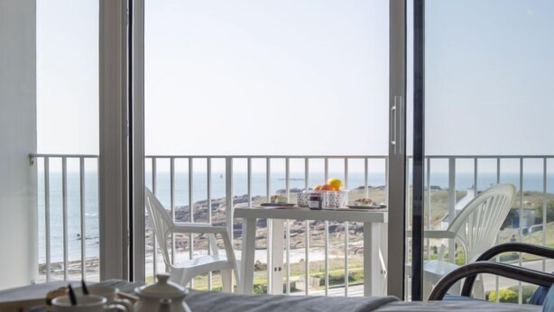 Un balcon avec une table préparée pour le petit-déjeuner, une chaise et un lit sur lequel se trouve un plateau avec des aliments pour le petit-déjeuner.
