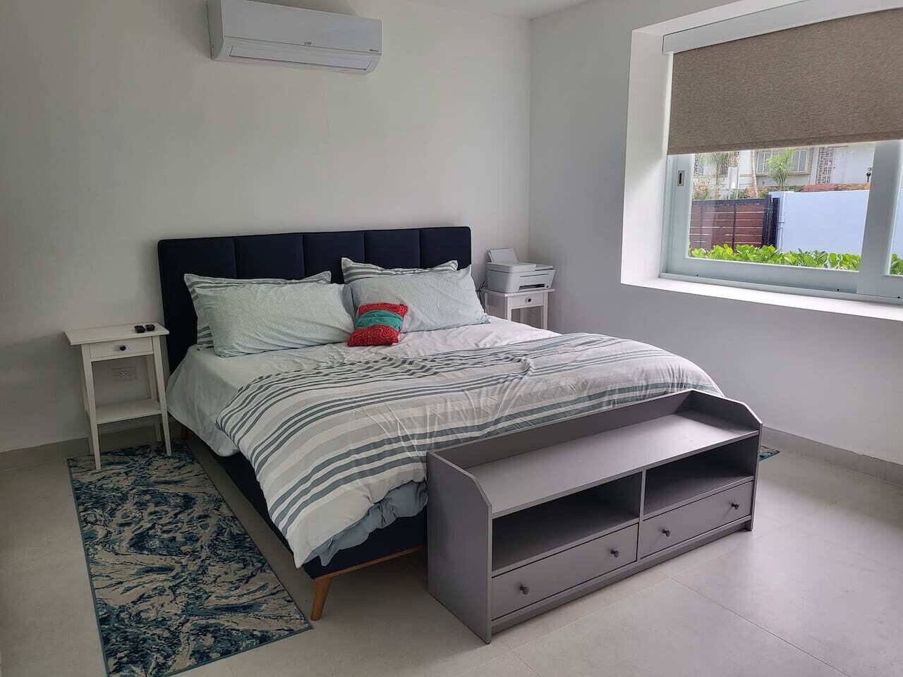 Une chambre à coucher comprenant un lit, des tables de chevet, une fenêtre et un banc intégré.