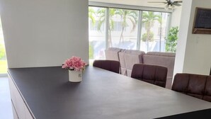 Ein moderner Essbereich mit einem großen schwarzen Tisch, beigen Stühlen und einer kleinen weißen Vase mit rosa Blumen.