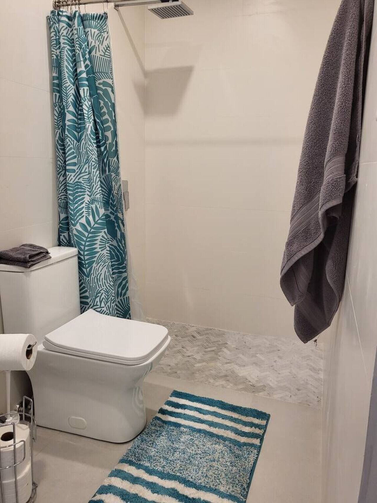 A compact bathroom with a shower, toilet, and a towel rack.