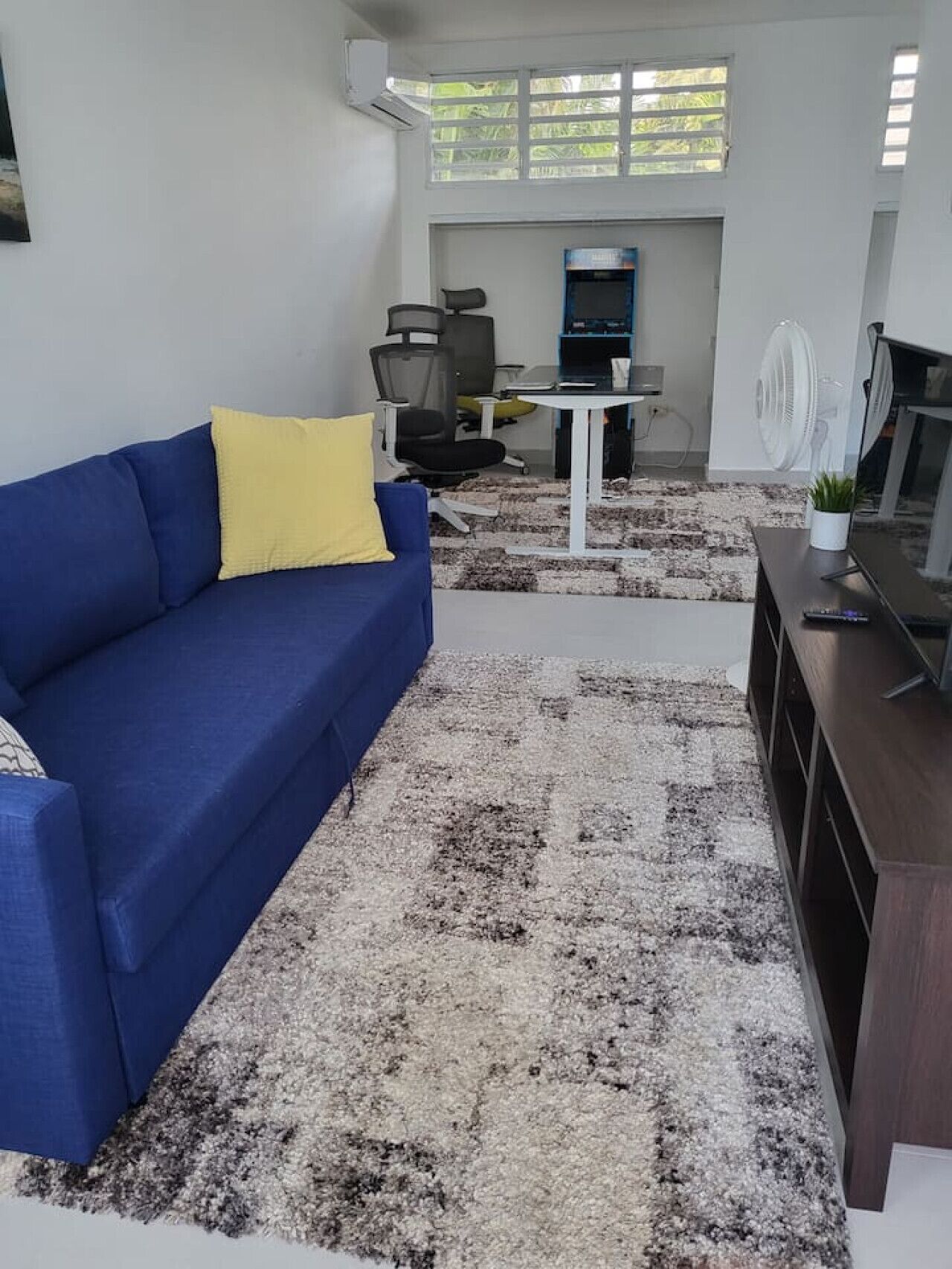A modern living room with a blue sofa, a small table, and a TV stand.