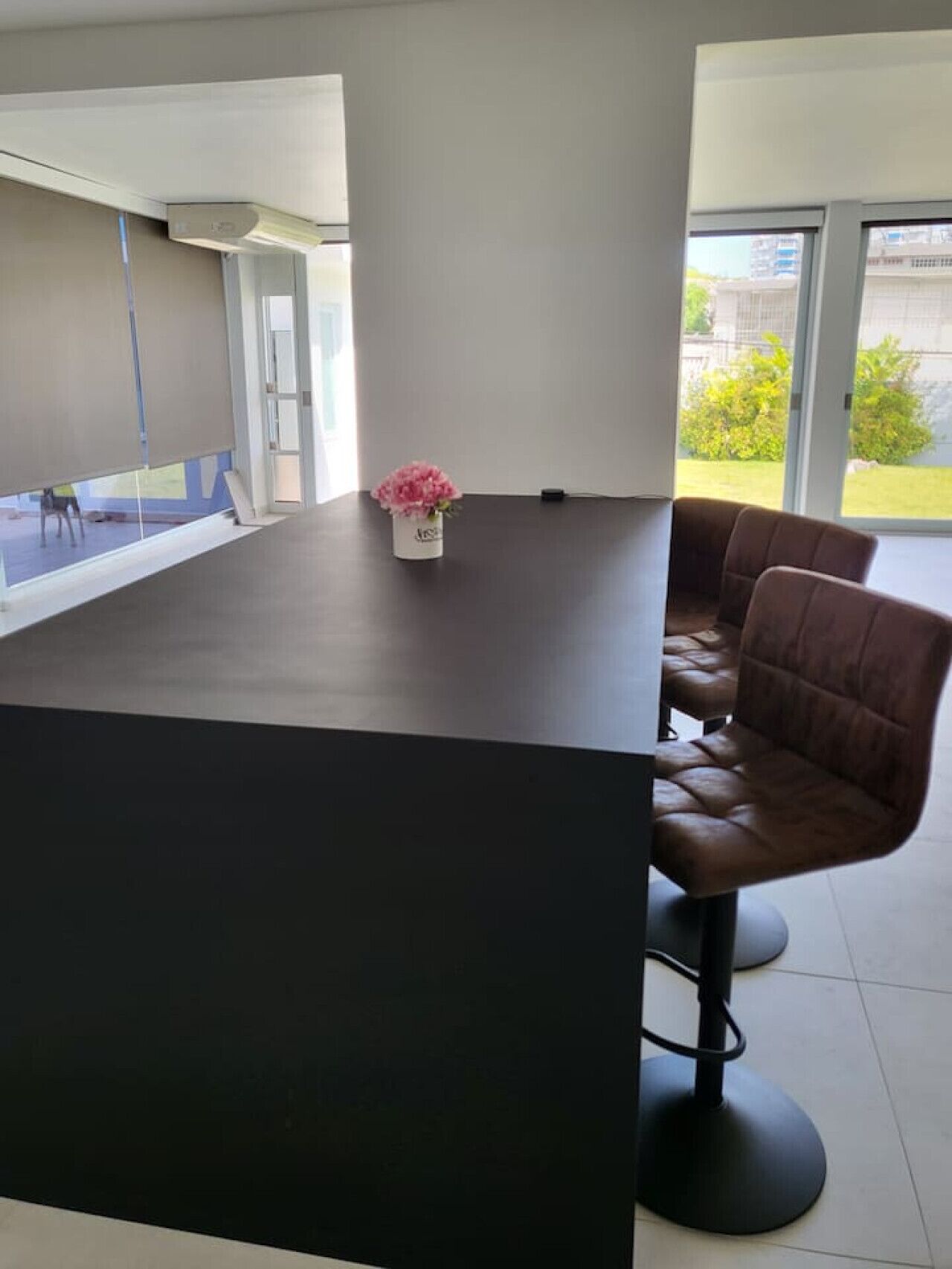 Uma sala de conferências moderna com uma mesa escura, duas cadeiras de couro e uma pequena planta em vaso.