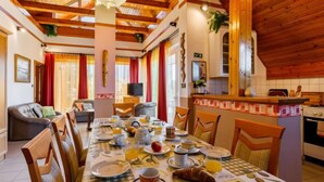 A cozy dining area with a checkered tablecloth, wooden chairs, and a breakfast setting. - Vacation home Szabo by Interhome (Balatonlelle)