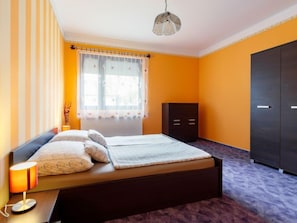 Ein Schlafzimmer mit einem Bett, einem Nachttisch, einer Lampe, einem Kleiderschrank und einem Fenster mit Vorhängen.