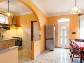 Enjoy meals in this kitchen with a gas stove, oven, and refrigerator, complemented by a dining area with a table and chairs.