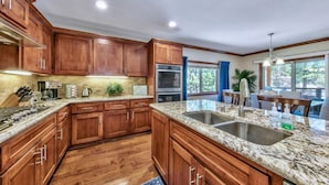 A kitchen with wooden cabinets, granite countertops, stainless steel appliances, and a view of the outdoors. - Prime Walk-to-Heavenly Townhome w/ A/C | TW702 (South Lake Tahoe)
