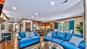A spacious living room with two blue sofas, a coffee table, and a kitchen area in the background. - Prime Walk-to-Heavenly Townhome w/ A/C | TW702 (South Lake Tahoe)