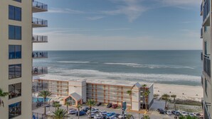 Un hotel con varias plantas, vista al mar y un estacionamiento con varios coches.