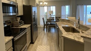 A modern kitchen with stainless steel appliances, a dining area with a view, and a large window.