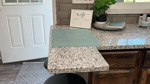 Une cuisine avec un comptoir en granit, un tabouret noir, une plante en pot et un panneau indiquant le mot de passe du réseau Wi-Fi.