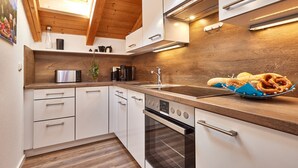 Eine moderne Küche mit weißen Schränken, einer Holz Arbeitsplatte, einem Einbauofen und einem Oberlicht.