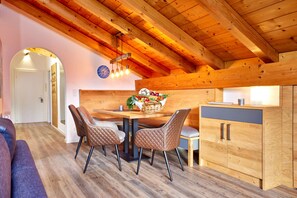 A cozy dining area with a wooden ceiling, a table with chairs, and a kitchen counter with cabinets.