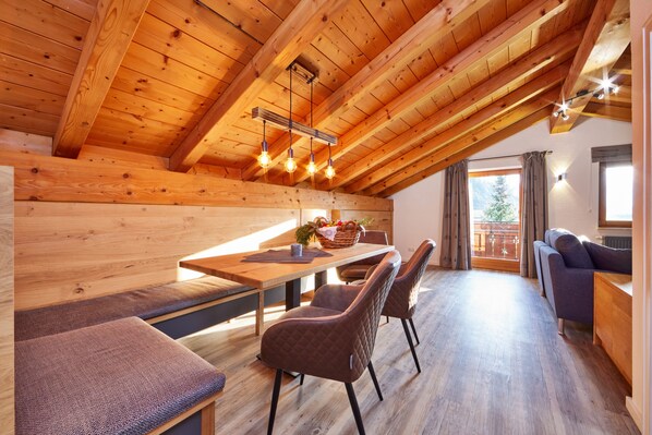 A wooden interior with a dining area, seating, and a view to the outside.