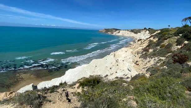 Un paysage côtier avec une plage de sable et des falaises rocheuses.