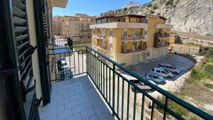 Un immeuble résidentiel doté de balcons, d’un espace de stationnement et offrant une vue sur une colline rocheuse.