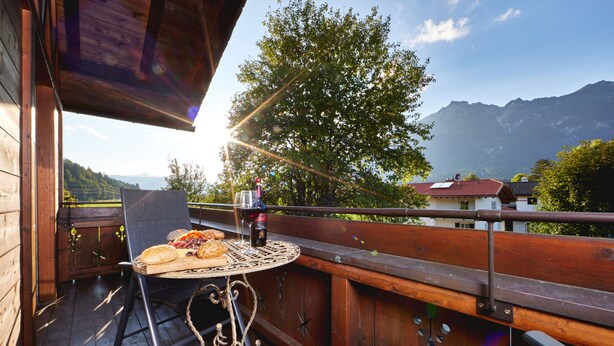 En träveranda med ett bord dukat för en måltid, med utsikt över ett bergigt landskap.