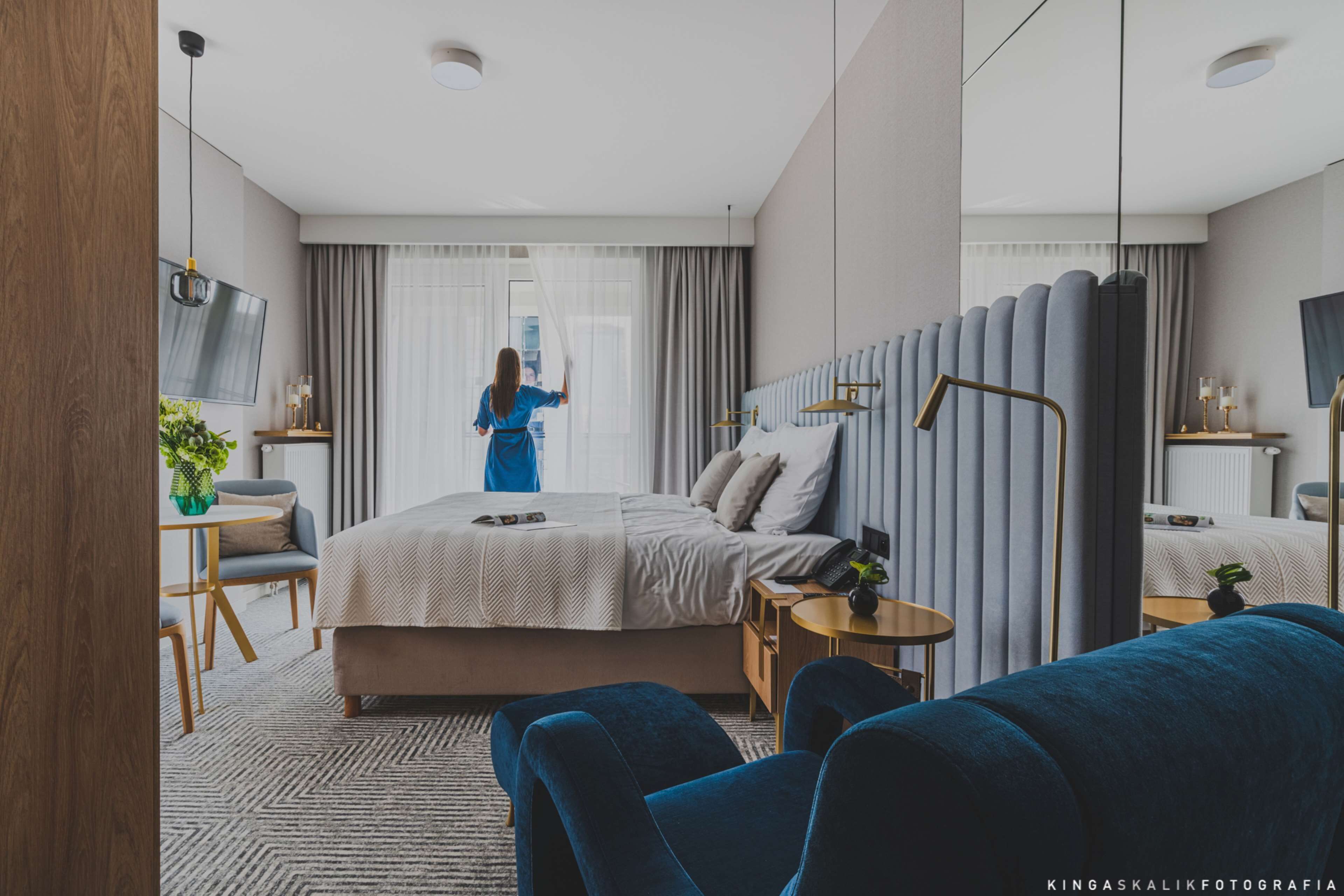 Una habitación de hotel moderna con una cama grande, un escritorio, una silla y un televisor.