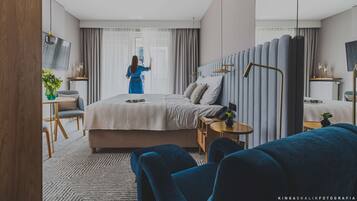 Ein modernes Hotelzimmer mit einem großen Bett, einem Schreibtisch, einem Stuhl und einem Fernseher.