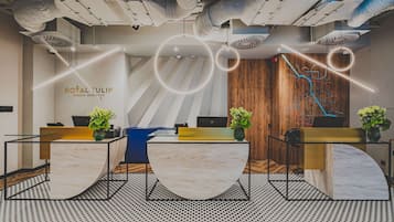 Een receptiezone met een modern ontwerp, met een receptiebalie, twee zithoeken en een houten accentmuur.