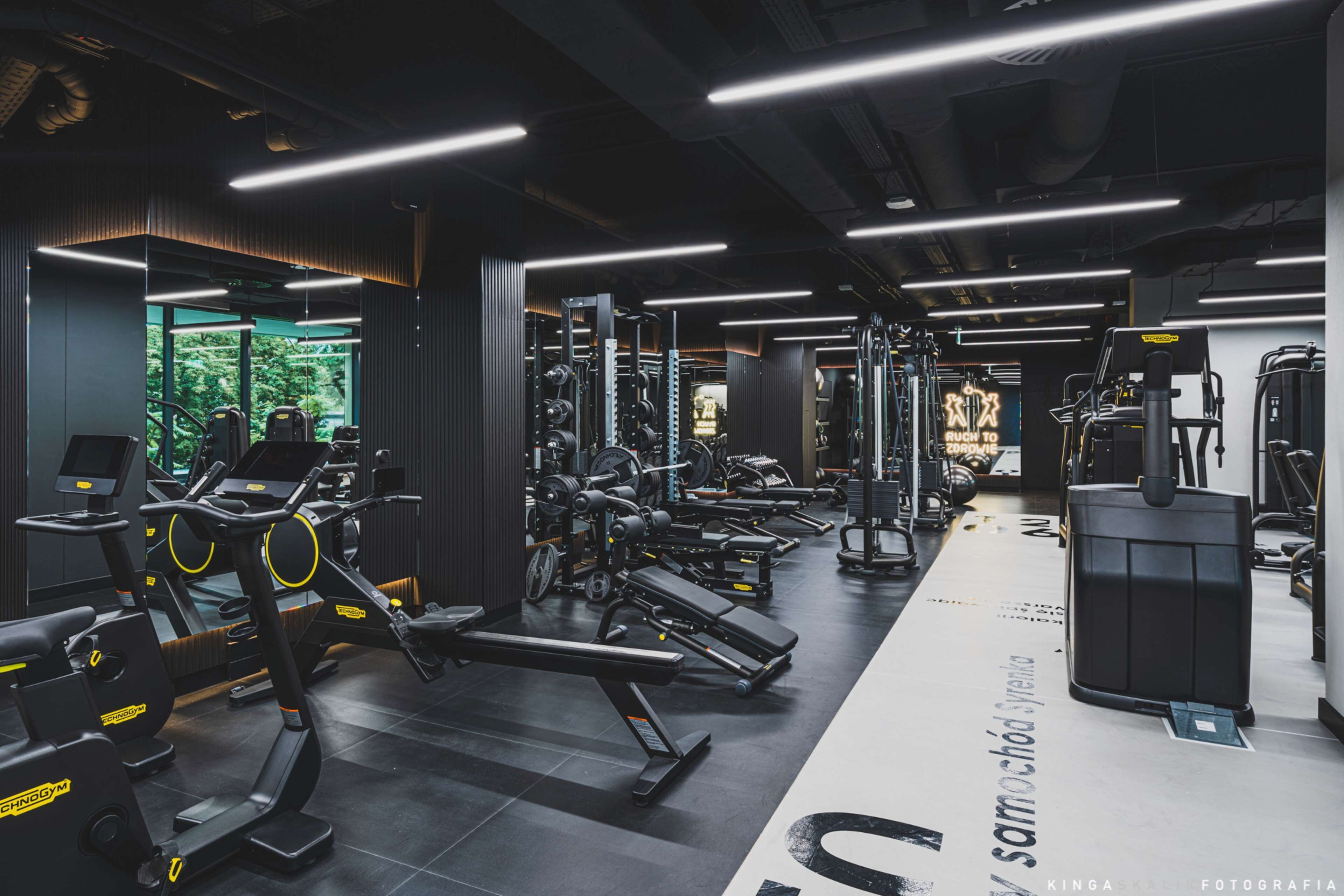 A modern gym with various exercise equipment, including treadmills, weight machines, and free weights.
