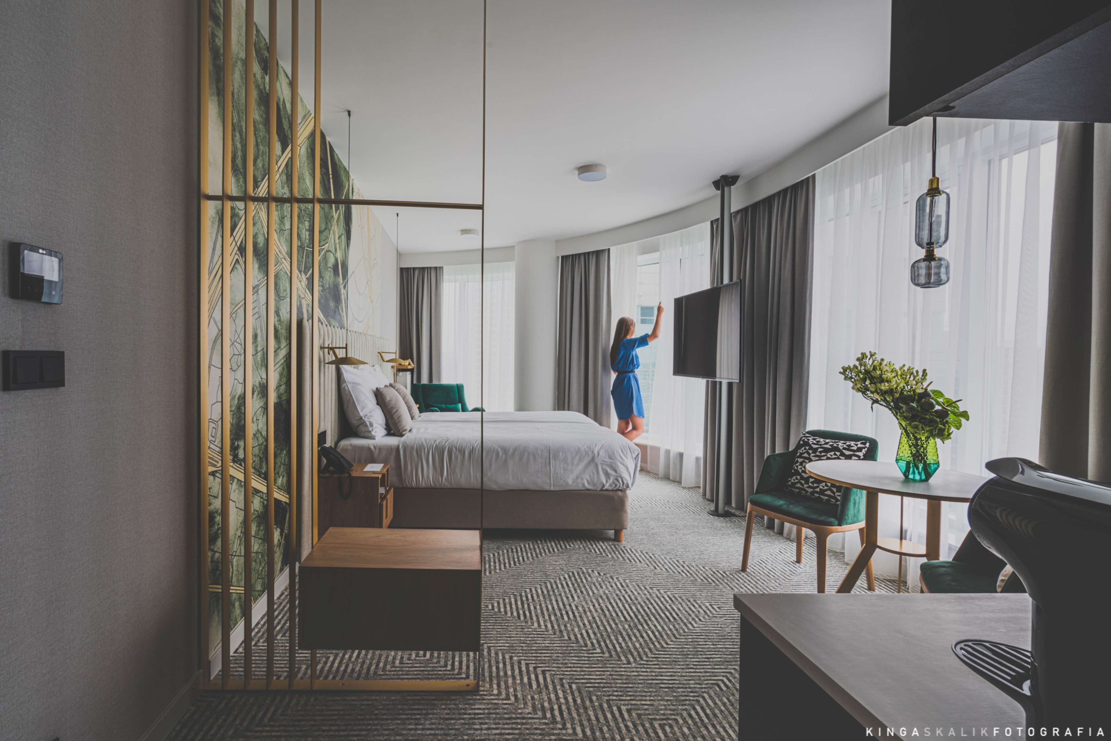 Una habitación de hotel moderna con una cama grande, un escritorio, una silla y un televisor.