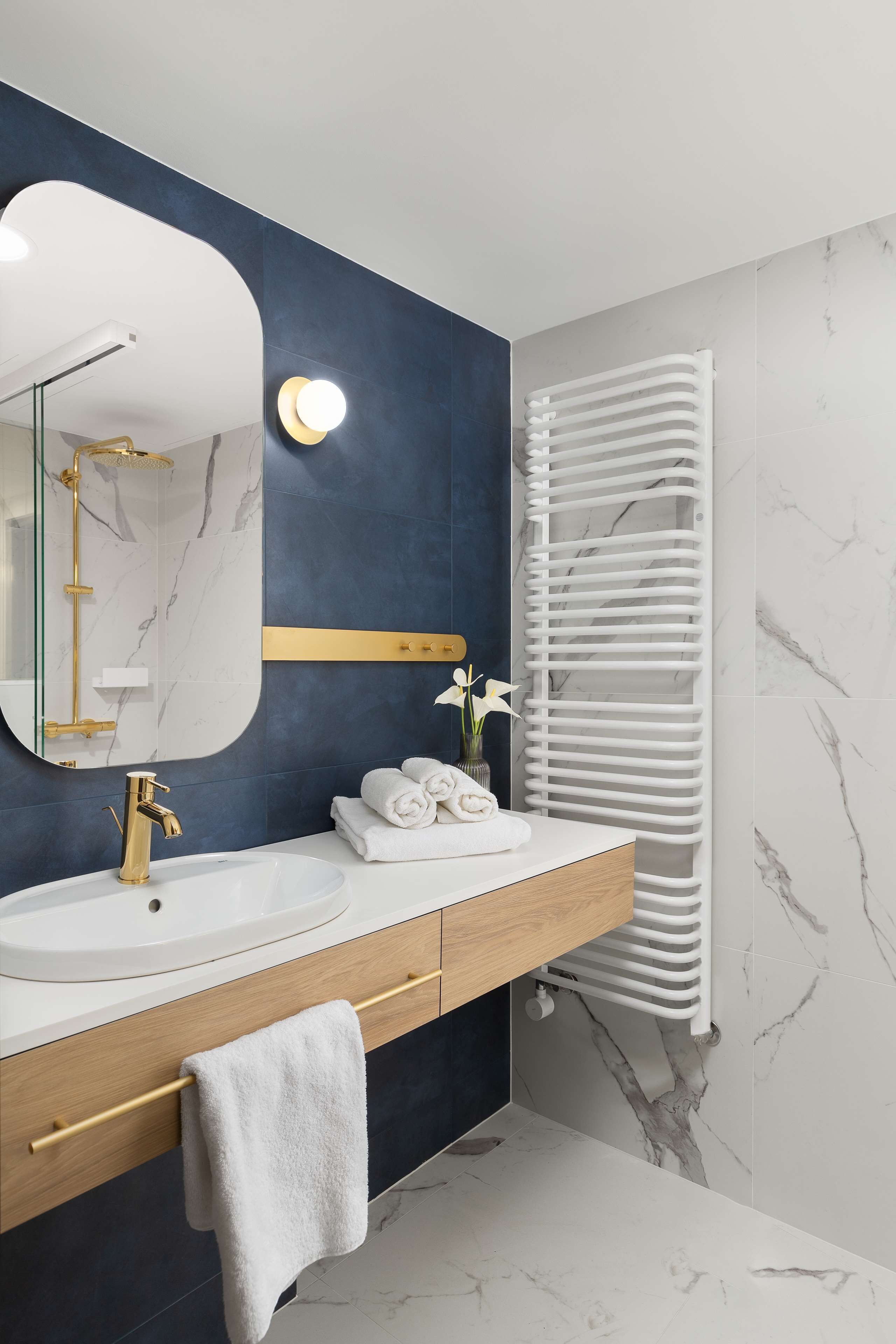 Ein modernes Badezimmer mit einem мраморному Waschbecken, goldenen Armaturen und einem Handtuchhalter.