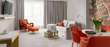 A modern living room with a sofa, armchairs, a coffee table, and a dining area with a table set for two.