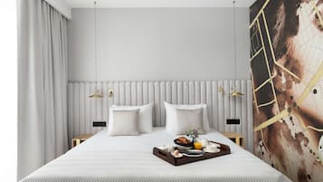 Habitación de hotel con una cama grande, dos mesitas de noche, una lámpara de pared y una bandeja de desayuno sobre la cama.