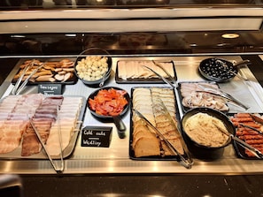 Enjoy a diverse selection of meats, vegetables, and dishes, carefully arranged on a buffet counter for easy selection.