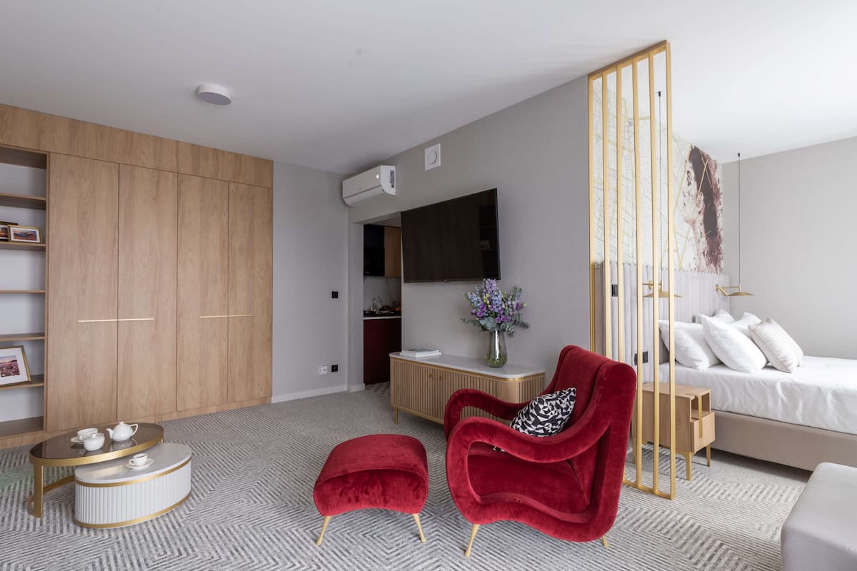 Un dormitorio moderno con una cama, una silla roja, una mesita y un armario.