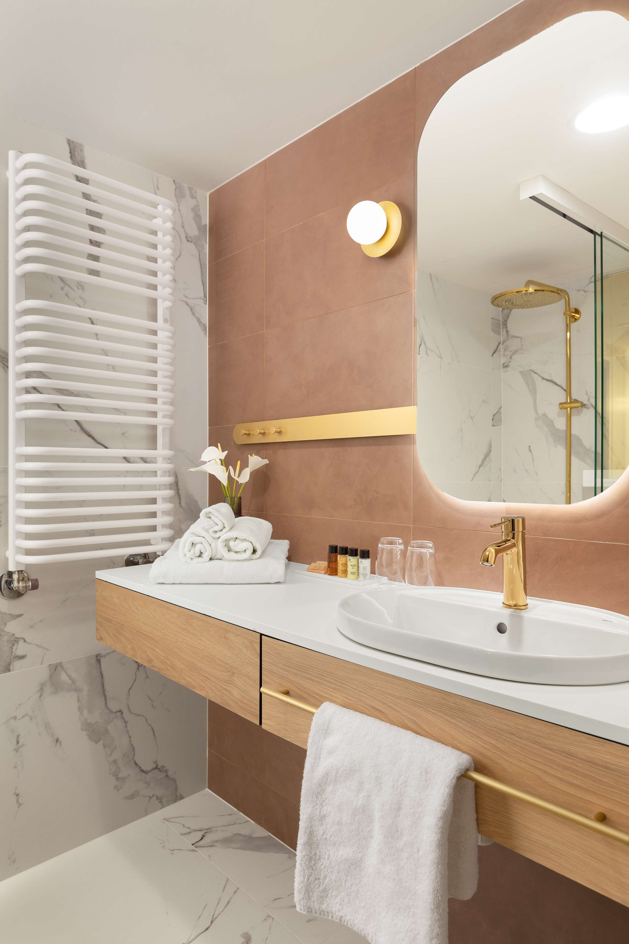 A modern bathroom with a white marble sink, gold fixtures, and a towel rack.