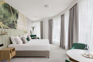 Relax in a spacious room with a large bed, round dining table, and comfortable seating area.