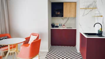 A compact kitchen with a checkered floor, a dining area with a table and chairs, and a small bar area with a sink.