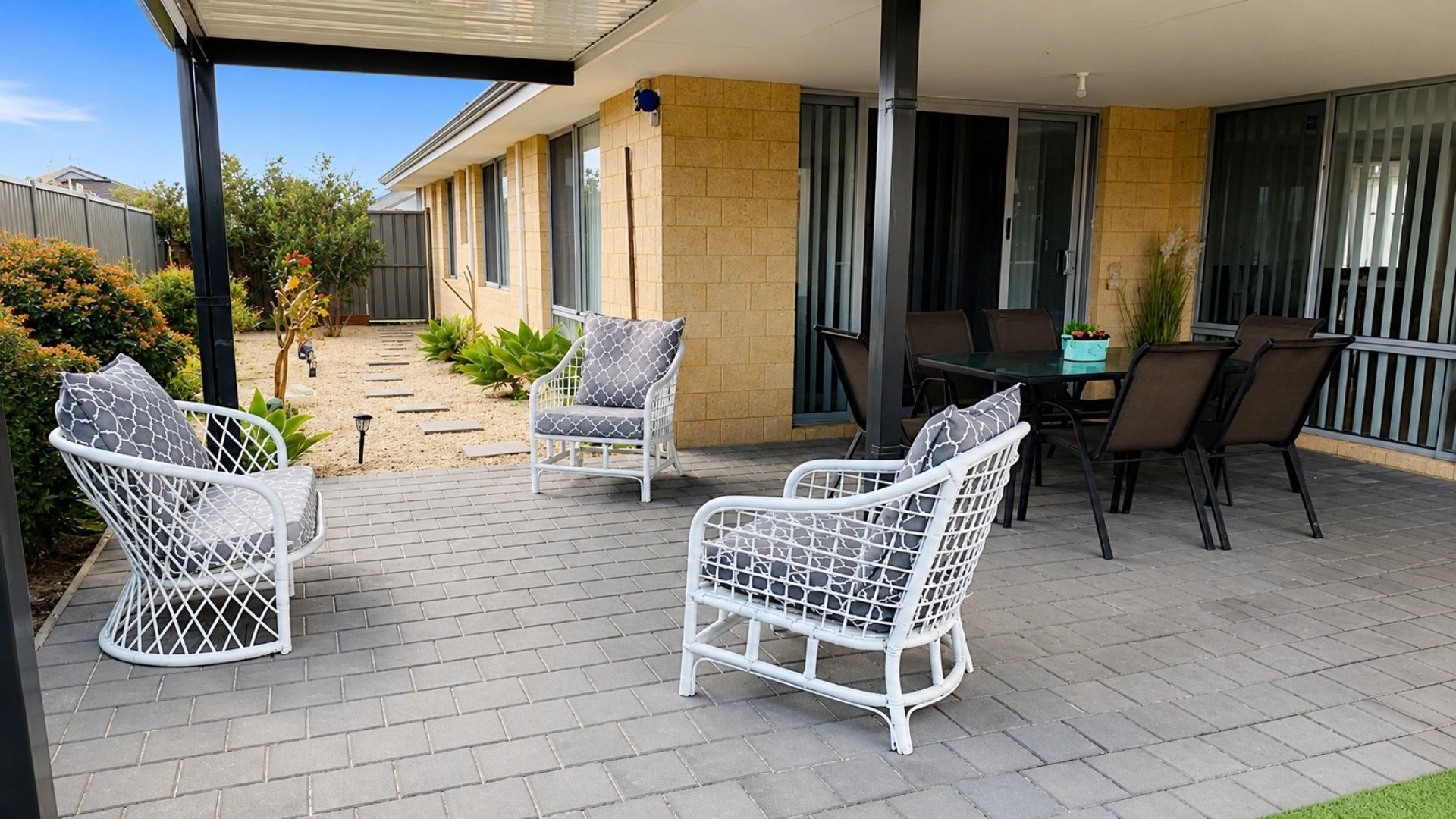 A covered patio with outdoor furniture, a table, and chairs.