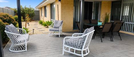 A covered patio with outdoor furniture, a table, and chairs.