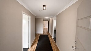 Ein Gang mit Holzboden, weißen Wänden und einem schwarzen Teppich.