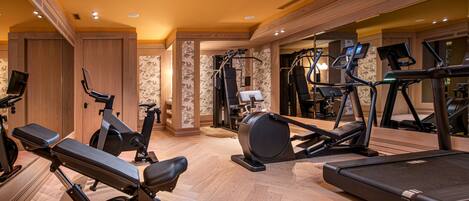 A spacious gym with various exercise equipment, including treadmills, stationary bikes, and weight machines.