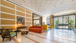 Un hall d’entrée spacieux au design moderne, avec un grand canapé orange, une chaise en bois et un fauteuil jaune.
